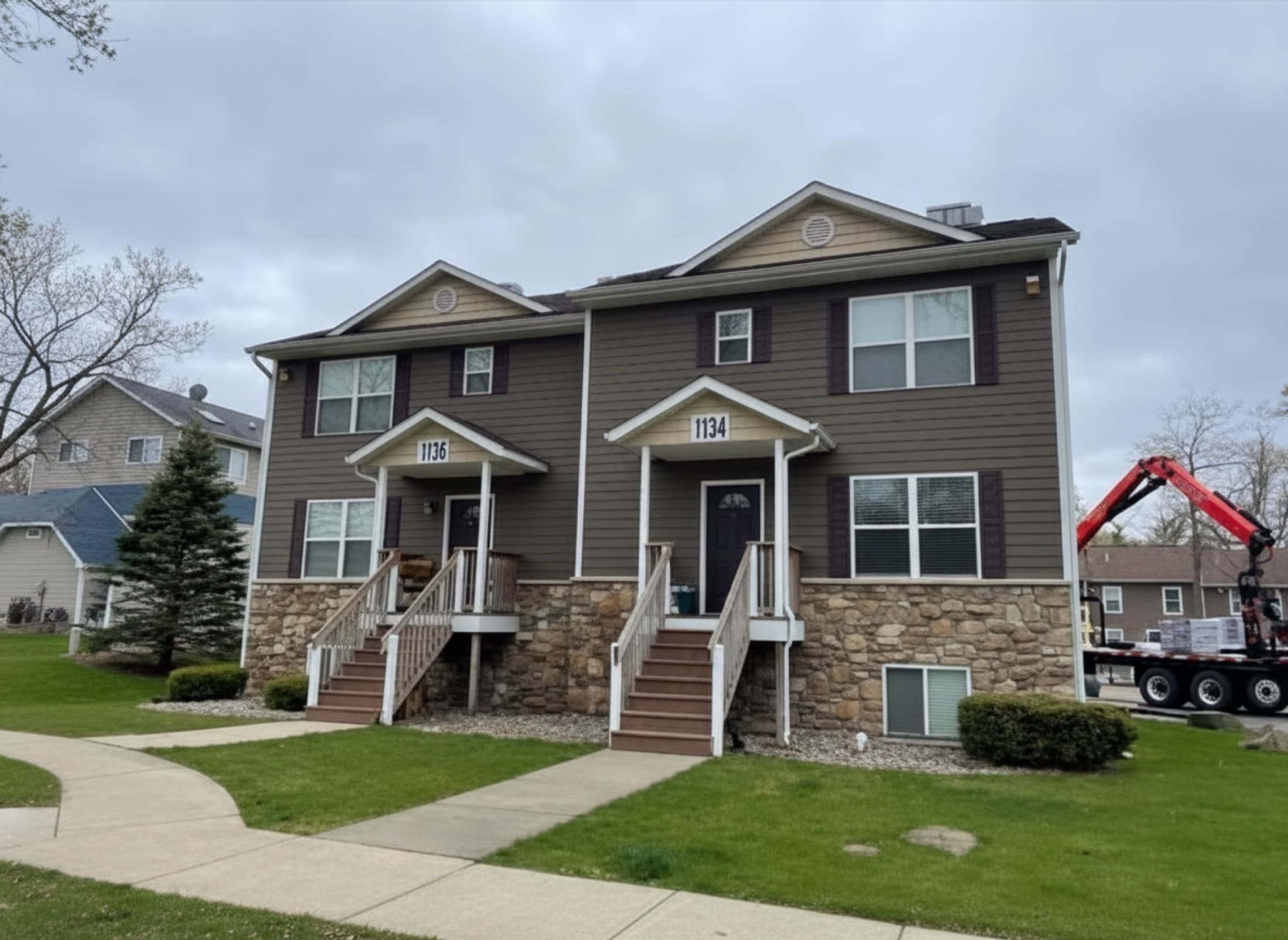 Finished duplex exterior with new siding, stone accents, and roof